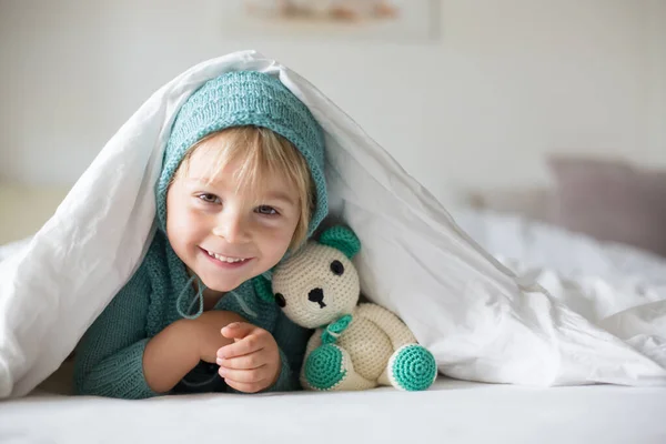 Aranyos Kisfiú Kézzel Kötött Játékkal Fekszik Ágyban Boldogan Mosolyog — Stock Fotó