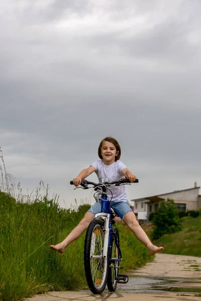 Kind Jongen Rijfiets Modderpoel Zomertijd Een Regenachtige Dag — Stockfoto