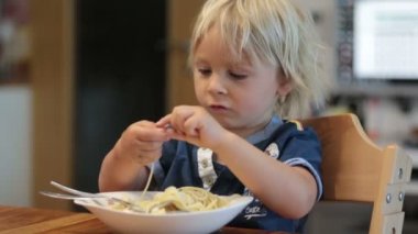 Tatlı sarışın çocuk, evde elleriyle spagetti yiyen çocuk.