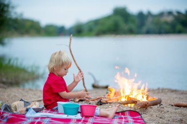 Aile piknik yapıyor ve yaz akşamları nehir kenarında kamp ateşi yakıyor.