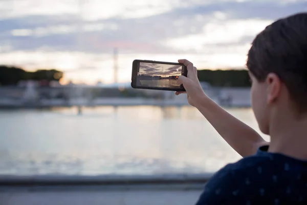 Niño Tomando Una Foto Con Teléfono Una Fuente París Atardecer — Foto de Stock