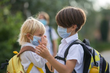 Okul çocukları, çocuklar, yaz tatilinden sonra okula geri dönmek, çocuklar Coronavirus COVID 19 yüzünden maske takarak okula gitmek.