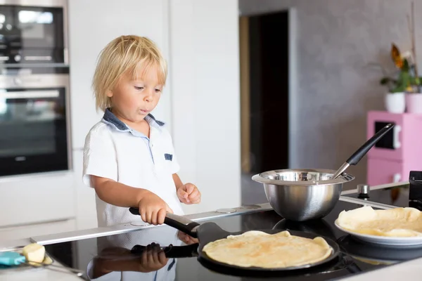 かわいい幼児の子供 ブロンドの男の子 台所でパンケーキを作り それらを食べる — ストック写真