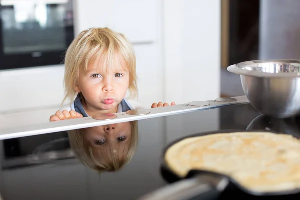 かわいい幼児の子供 ブロンドの男の子 台所でパンケーキを作り それらを食べる — ストック写真