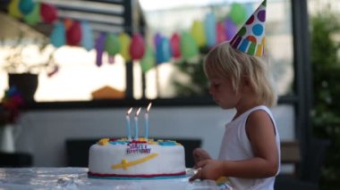 Sevimli mutlu çocuklar, küçük çocuklar evde balonlarla, kardeşlerle ve renkli ev yapımı pastalarla doğum gününü kutluyorlar..