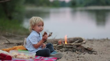 Aile, çocuk piknik yapıyor ve yaz akşamları nehir kenarında kamp ateşi yakıyor.