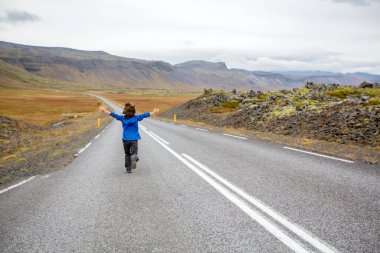 Çocuk, İzlanda 'daki Snaefellsjokull Ulusal Parkı' nda güzel bir yolda sonbaharda koşuyor.