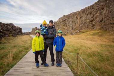 Üç çocuklu baba, Thingvellir Ulusal Parkı Yarık Vadisi, İzlanda 'da güneşli bir günün tadını çıkarıyor.