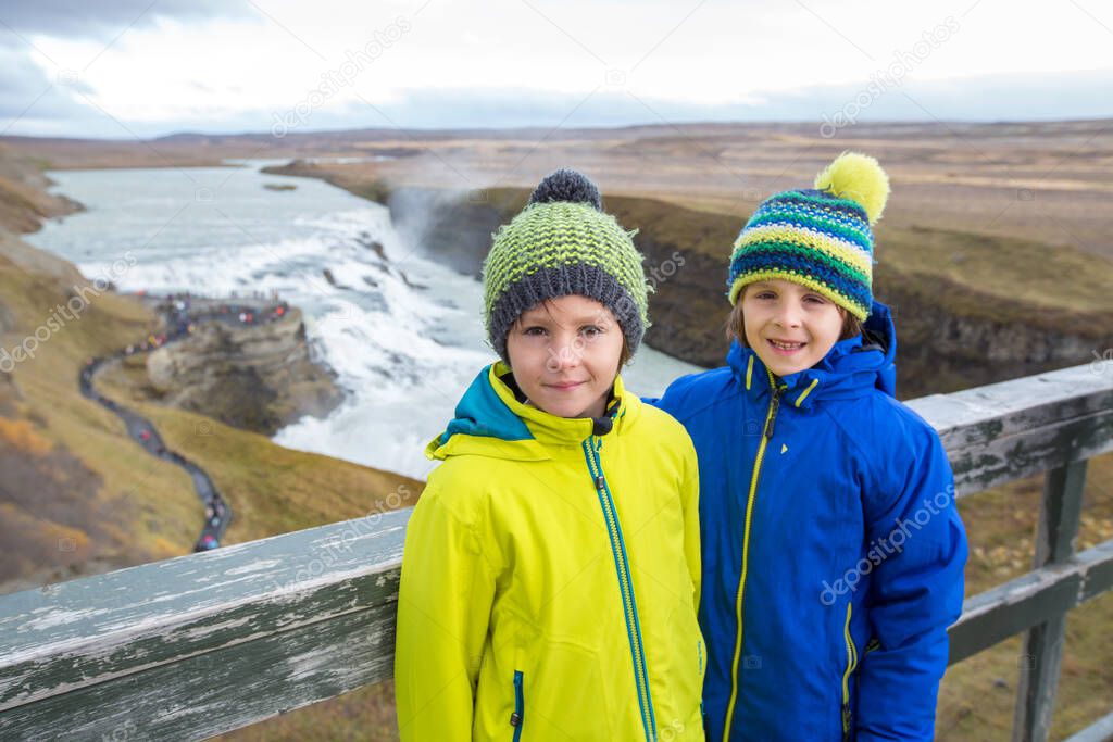 Children, enjoying the big majestic Gullfoss waterfall in mountains in Iceland, autumntime