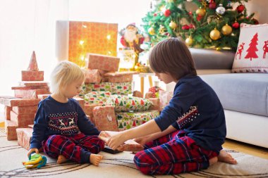Mutlu çocuklar, çocuklar, Noel günü hediyeleri açıyorlar, pijama giyiyorlar.