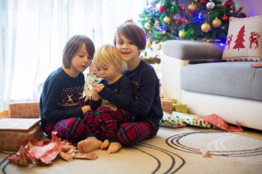 Mutlu çocuklar, çocuklar, Noel günü hediyeleri açıyorlar, pijama giyiyorlar.