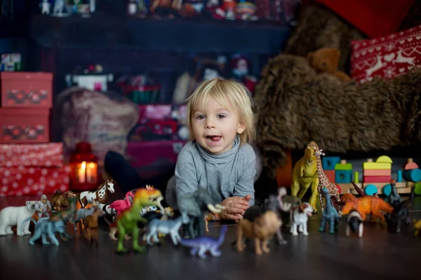 可爱的金发碧眼的小孩 在家里和塑料动物和恐龙玩耍 身边的圣诞装饰品 — 图库照片