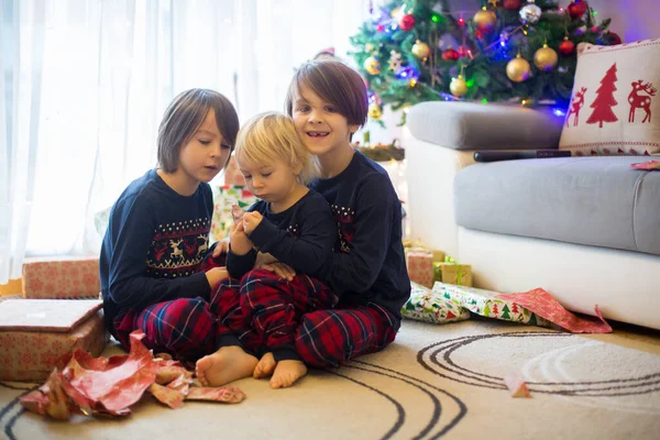 Mutlu çocuklar, çocuklar, Noel günü hediyeleri açıyorlar, pijama giyiyorlar.