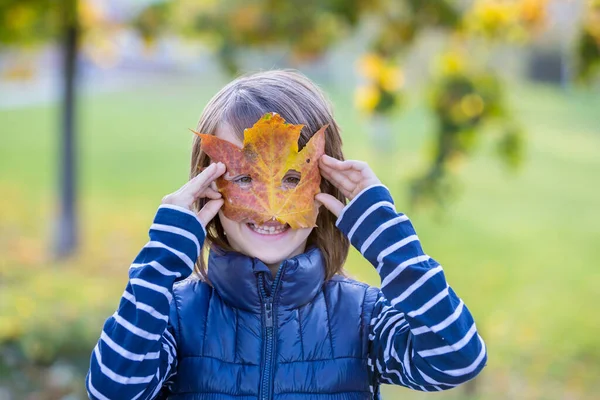 Güzel Anaokulu Çocuğu Suratının Önünde Koca Bir Yaprak Tutuyor Kameraya — Stok fotoğraf