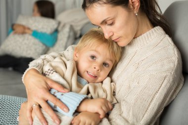 Anne ve çocuk, sarışın çocuk, evdeki kanepede uzanıyor, sarılıyor.