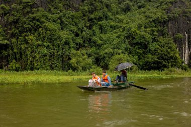 Avrupalı bir aile, Ninh Binh 'i ziyaret ediyor, yürüyüş yapıyor, bisiklete biniyor, tekne gezisine çıkıyor, Vietnam' da yaz tatilinin keyfini çıkarıyor.