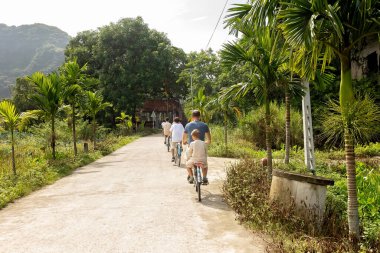 Avrupalı bir aile, Ninh Binh 'i ziyaret ediyor, yürüyüş yapıyor, bisiklete biniyor, tekne gezisine çıkıyor, Vietnam' da yaz tatilinin keyfini çıkarıyor.