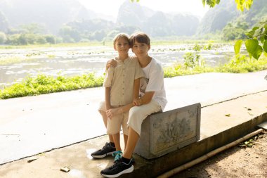 Avrupalı bir aile, Ninh Binh 'i ziyaret ediyor, yürüyüş yapıyor, bisiklete biniyor, tekne gezisine çıkıyor, Vietnam' da yaz tatilinin keyfini çıkarıyor.