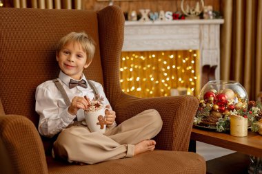 Tatlı sarışın çocuk, tatlı çocuk, Noel 'de Noel oyuncaklarıyla oynayan, Noel için güzel dekore edilmiş ev, ışıklarla dolu rahat bir yer.