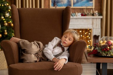 Tatlı sarışın çocuk, tatlı çocuk, Noel 'de Noel oyuncaklarıyla oynayan, Noel için güzel dekore edilmiş ev, ışıklarla dolu rahat bir yer.