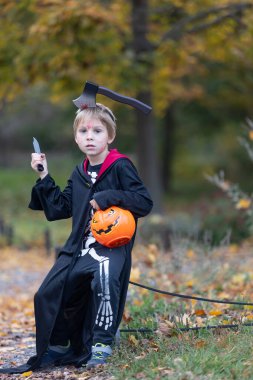 Cadılar Bayramı kostümlü bir ormanda çocuk, mumlarla ve dekorasyonla oyulmuş balkabakları, ürkütücü konsept, Cadılar Bayramı teması