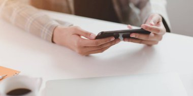 Akıllı telefonu tutan genç iş kadınının yakın çekim görüntüsü 