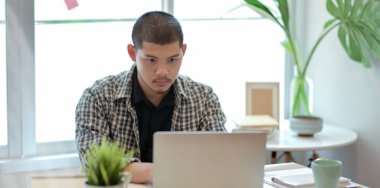 Dizüstü bilgisayar kullanırken projesi üzerinde çalışan tasarımcı 