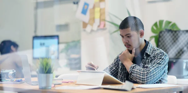 Jonge mannelijke ontwerper werkt aan zijn project tijdens het gebruik van Tablet — Stockfoto