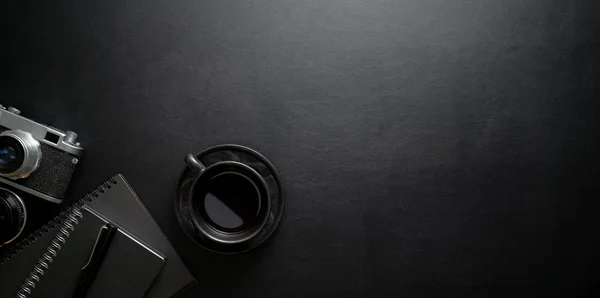 Dark stylish workplace with coffee cup and office supplies on bl