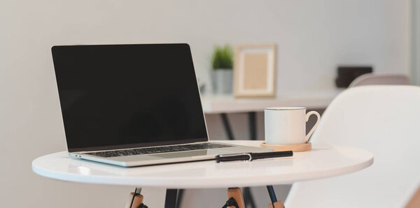 Open blank screen laptop computer in minimal workplace with coff
