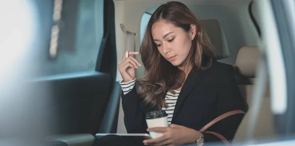 Joven mujer de negocios trabajadora trabajando en el coche con una taza o — Foto de Stock