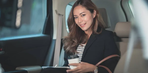 Atractiva mujer de negocios trabajando en el coche con una taza de café — Foto de Stock