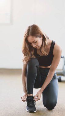 Genç ince fitness kız spor salonunda ayakkabı bağcıkları yapıyor