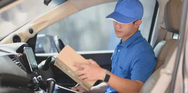 Young delivery man checking orders while preparing the products — Stock Photo, Image