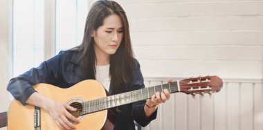Evde boş zamanlarında akustik gitar çalan güzel kadın