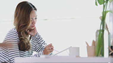 Genç tasarımcı tablet üzerinde projesini düzenleme ve gülümseyerek 