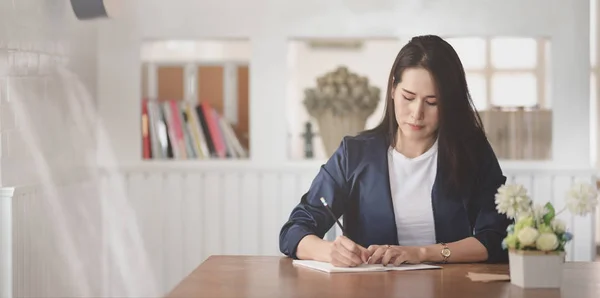 Professionelle Geschäftsfrau, die an ihren Projekten arbeitet, während sie ihre Idee am Notizbuch schreibt. — Stockfoto