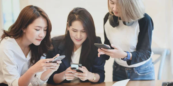 Female freelancers sharing information on smartphone to other team members. — Stock Photo, Image