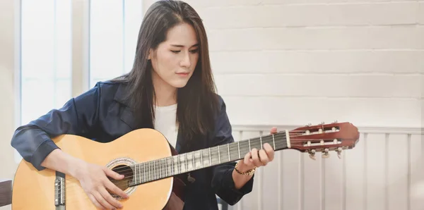 Mooie vrouw speelt akoestische gitaar in haar vrije tijd thuis — Stockfoto