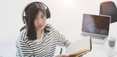 Müzik dinlerken ve kameraya bakarken projesi üzerinde çalışan genç sevimli kadın 