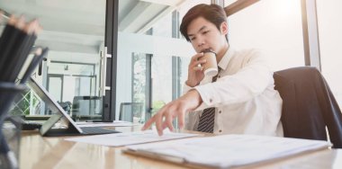 Bir fincan kahve içerken projesi üzerinde çalışan genç profesyonel işadamı 