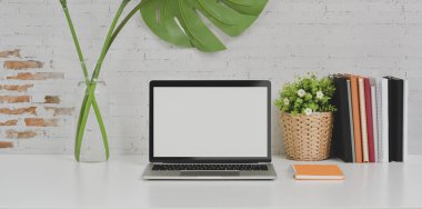 Beyaz masa üzerinde rahat tasarımcı işyeri dizüstü bilgisayar ve ofis malzemeleri