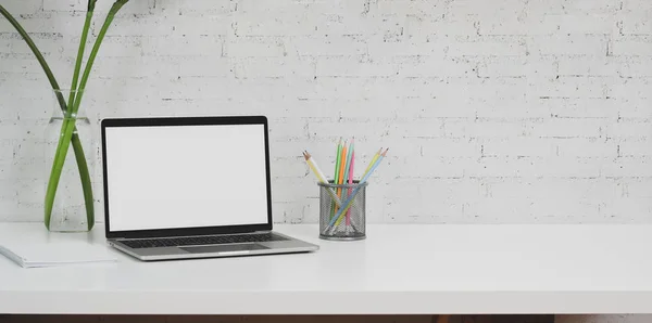 Beyaz masa üzerinde dizüstü bilgisayar ve ofis malzemeleri ile minimal tasarımcı işyeri 