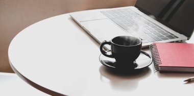 Beyaz masa üzerinde açık dizüstü bilgisayar, kahve fincanı ve ofis malzemeleri ile işyeri