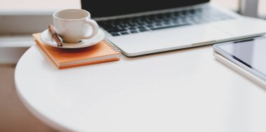 Beyaz masada dizüstü bilgisayar ve kahve fincanı ile minimal rahat işyeri