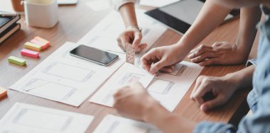 Genç profesyonel Ui grafik tasarımcı grubu birlikte akıllı telefonlar şablonları üzerinde tartışıyor  