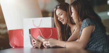 Alışveriş merkezinde alışveriş zaman geçirdikten sonra iki güzel Asyalı kadın akıllı telefon kontrol 