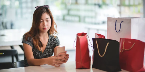 Азиатки проверяют свой смартфон после прогулок по магазинам в торговом центре — стоковое фото