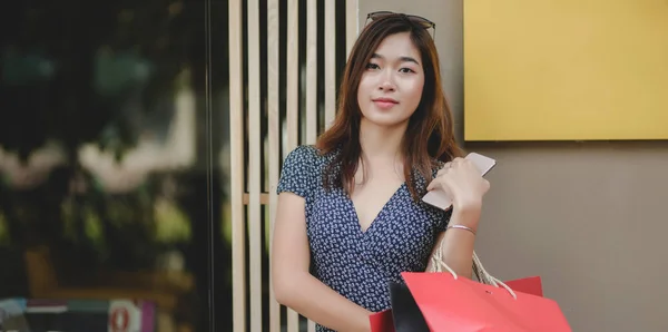 Portret van mooie Aziatische vrouw houdt haar Smartphone en boodschappentas na het winkelen in het winkelcentrum — Stockfoto