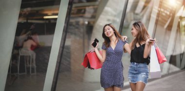 Alışveriş merkezinde alışveriş yaparken birlikte konuşan iki güzel Asyalı kadın 